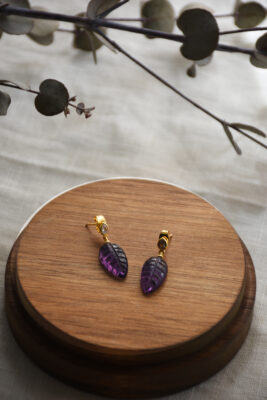 Ohrring in Gold mit Amethyst vom Luzerner Label Pink Sand. Messing vergoldet, nickelfrei mit Stecker. Modernes, feminines Design in Blattform, bestehend aus Amethyst. Oberhalb mit einem kleinen Zirkonstein.