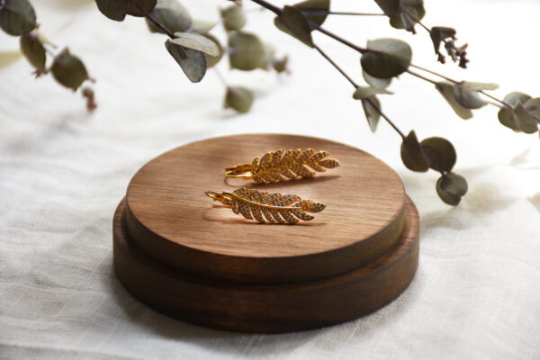 Ohrring aus Gold mit Zirkonia vom Luzerner Label Pink Sand. Messing vergoldet, nickelfrei mit Klappverschluss. Modernes, feminines Design in Federform mit Zirkonia-Steinchen.