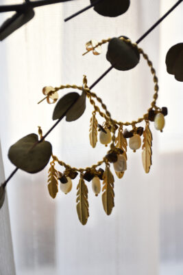 Ohrring aus Gold mit Tiegerauge und Perlmutt vom Luzerner Label Pink Sand. Messing vergoldet, nickelfrei mit Stecker. Modernes, feminines Design - gedrehte Kreolen mit Federn und Halbedelsteinen.