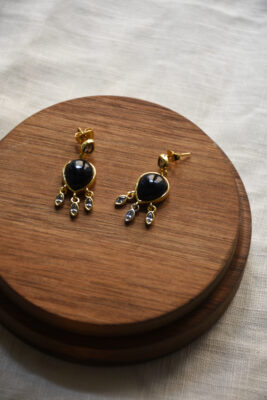 Ohrring aus Gold mit Black Spinel und Zirkonia vom Luzerner Label Pink Sand. Messing vergoldet, nickelfrei mit Stecker. Modernes, feminines Design in Tropfenform mit kleinen hängenden Steinchen.